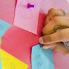 Person pins post-it note on wall