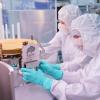 People in protective suits place a plaque on a space instrument in a clean room