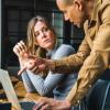 Two people talking over laptop computer