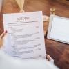 A women holding a sheet of paper that reads resume