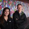Student with mentor, posing in front of colorful mural