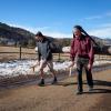 James Wilson and Rodger Kram carry a log from their heads using tumplines with the Boulder Foothills in the background