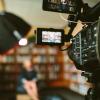 Person sitting, facing a video camera, bookshelves in the backgrounnd. (Sam McGhee/Unsplash)