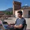 person works on laptop sitting on a campus rooftop