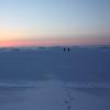 Researchers walking on sea ice at sunset