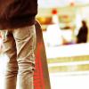 A skateboard is propped up near someone's legs, wearing jeans.