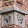 A stone column engraved with a CU symbol.