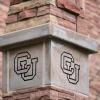 A stone column engraved with a CU symbol.