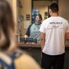 Staff member wearing a mask helps a student on campus