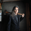 CU English Professor Stephen Graham Jones holds ax over shoulder