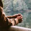 person leaning against a railing with hands folded