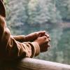 Arms rest over an outdoor railing, hands clutched.