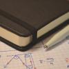 Notebook and graph paper with equations, sketches