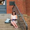 A woman sits on the steps of Old Main and reviews a notebook