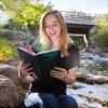 Woman reading book by creek