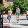 Student riding a bike on campus, while a friend walks alongside him