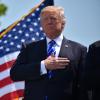 President Donald Trump placed hand over heart with flag in background