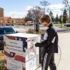 student dropping off a ballot in a dropbox