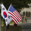 Republic of Korea and U.S. flags fly side by side, soldiers in background