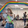Student helps set up a workshop with rainbow painted on a window
