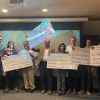 Competition winners hold giant checks.