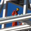 A construction worker in a helmet is seen surrounded by steel framing.