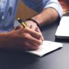 A person taking notes on a notepad