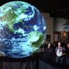 Onlookers observe a giant glowing globe at Fiske Planetarium