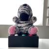 A stuffed zebra toy sits on a box with buttons