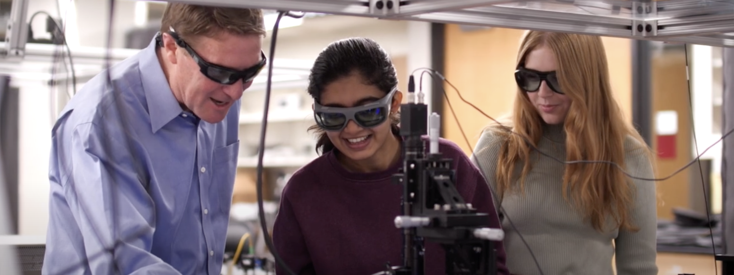 A man and two women examine scientific equipment in a lab