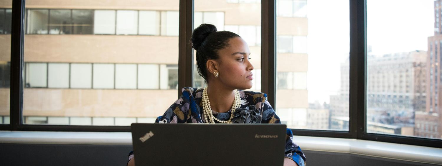 Employee sitting in front of a computer, looking out the window.