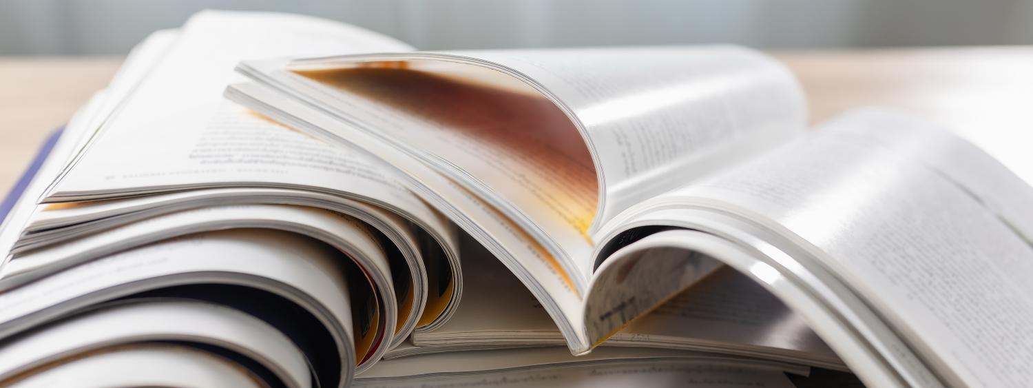 Stack of glossy magazines sitting open on a table