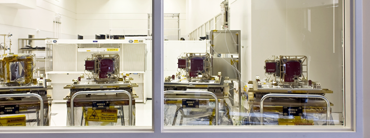 Four machines sit on carts on the other side of a glass window
