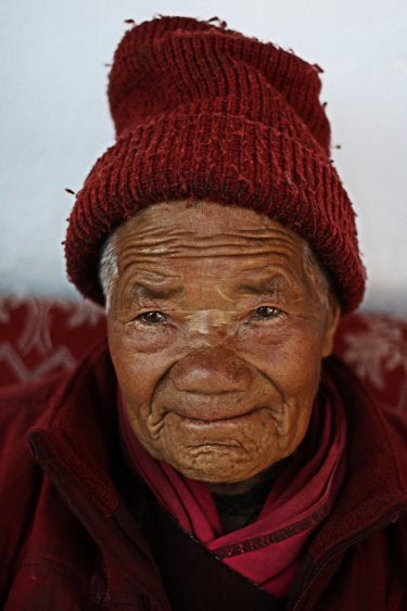 A photo of an elderly Indian woman wearing a red knitted hat
