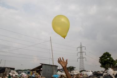 A photo of a yellow balloon and a hand reaching toward it