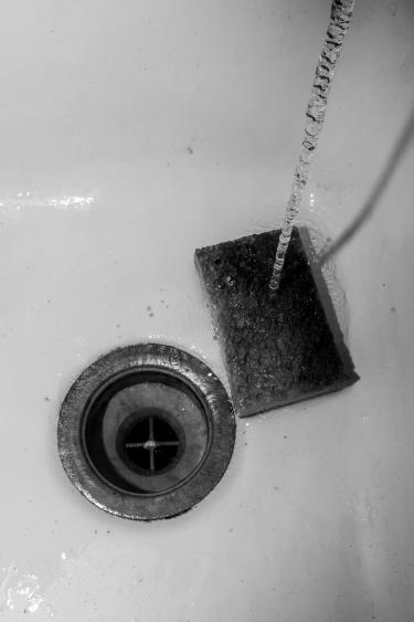 A black-and-white photo of a sponge in the bottom of a sink