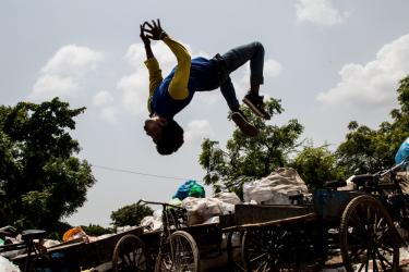 A photo of a man doing a backflip over a pile of trash
