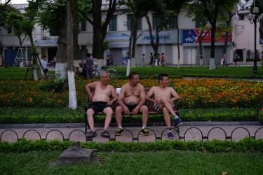 A photo of three shirtless men on a park bench