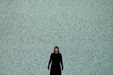 A photo of a woman dressed in black in front of a tile wall