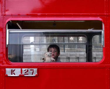 A photo of a child and teddy bear on a red bus