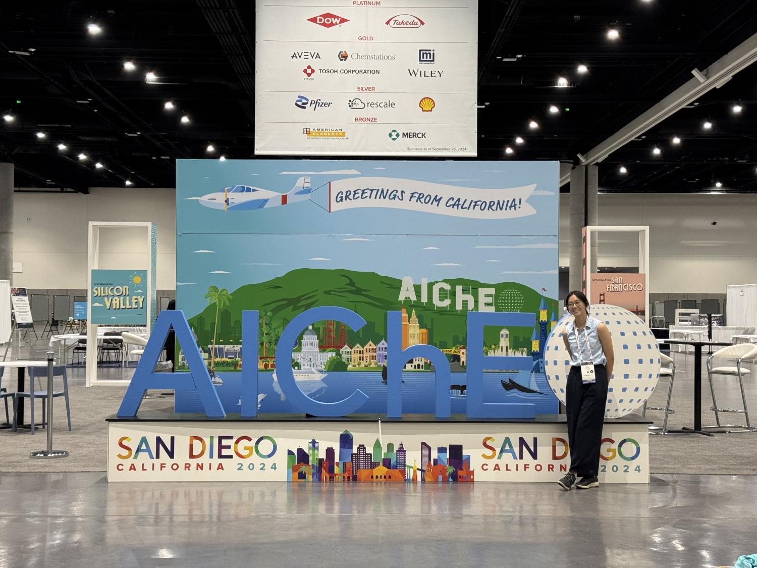 Student posing with conference display