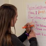 woman writing on sticky notes near whiteboard