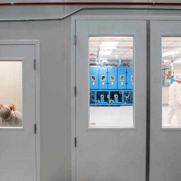 A person puts on a head covering and lab suit before entering a clean room.