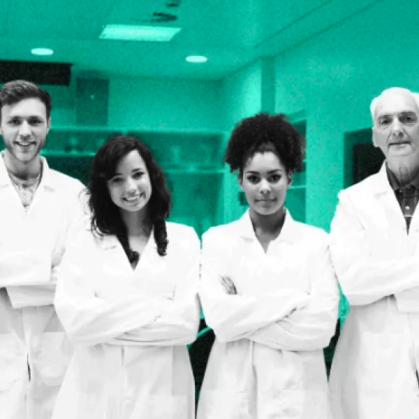 A diverse group of people wearing lab coats poses for a photo