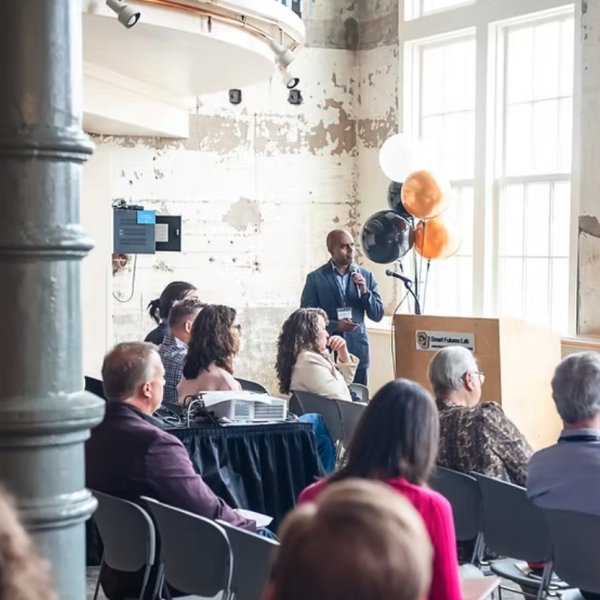 People in a modern industrialized space listen to a business presentation.