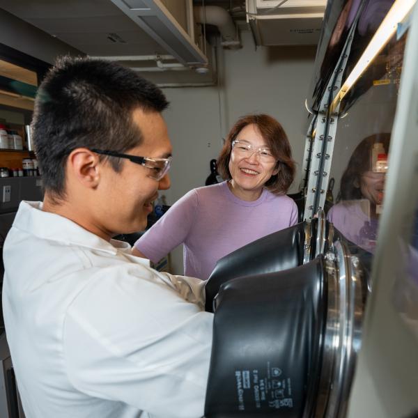 A man and a woman laugh while working together to in a laboratory