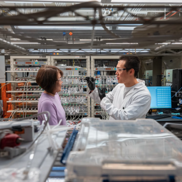 Two researchers, a woman and a man, examine a small device he holds up in a laboratory.