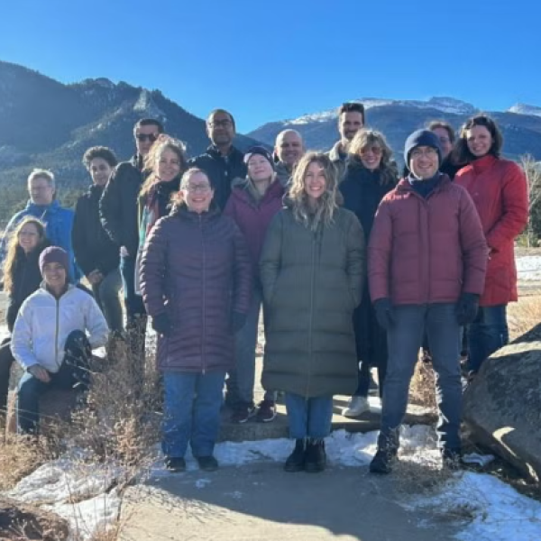 A group of people wearing winter clothes pose for a picture in the mountains