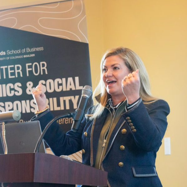 A woman gives a cheerful speech at a lectern, hands upheld