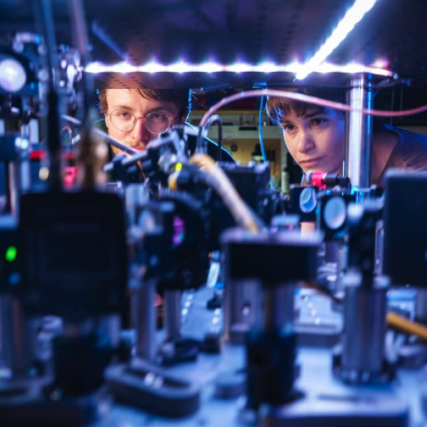 Two people peer inside a complex machine